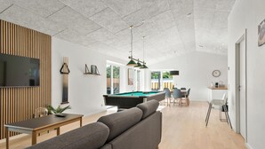 Una sala de estar moderna con billar, un sofá y una televisión.