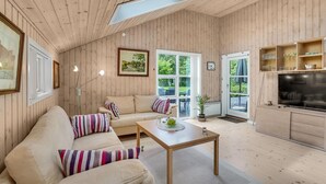 Un intérieur chaleureux, avec des boiseries, un canapé, une table basse et un téléviseur.