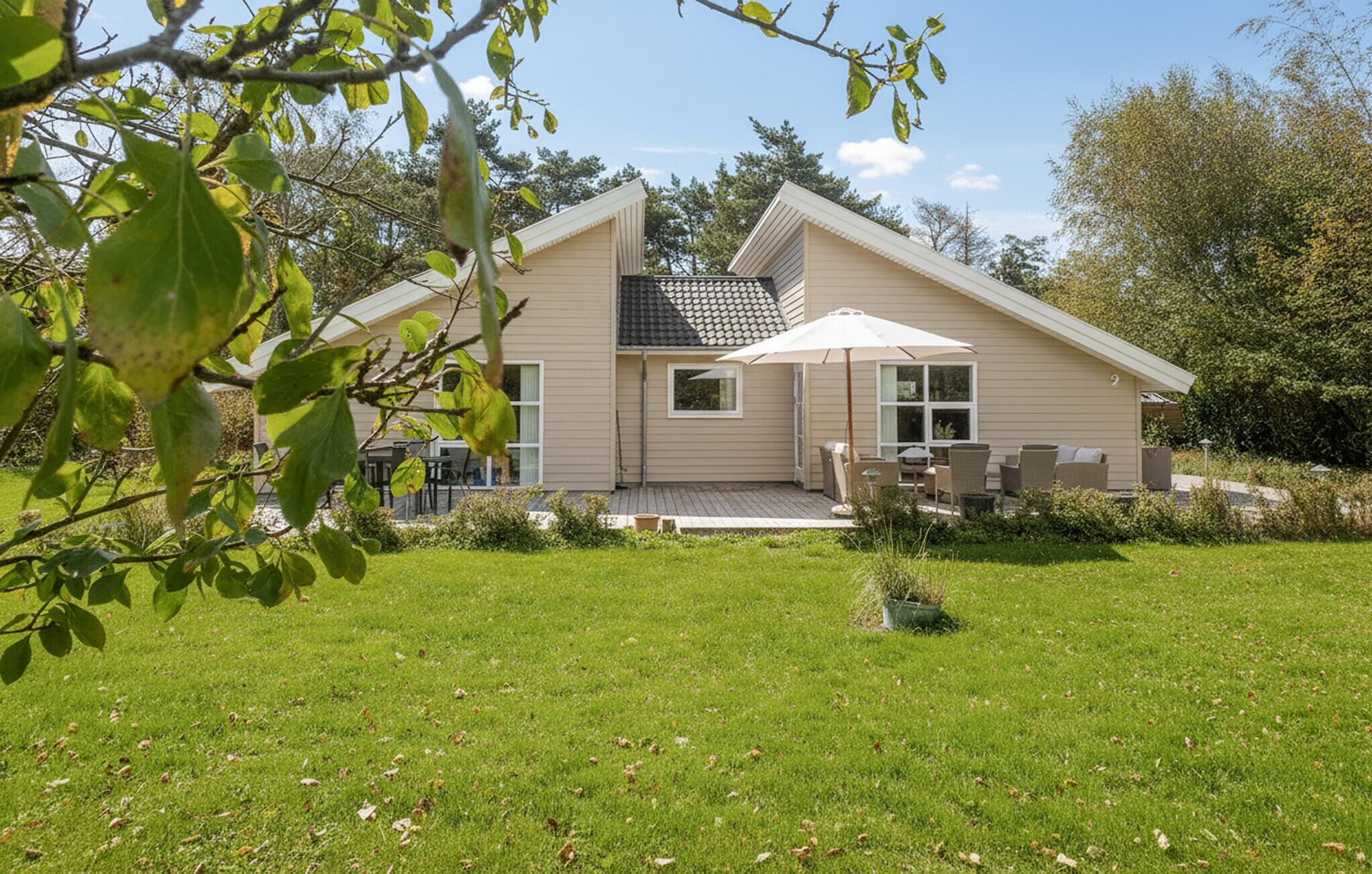 A two-story house with a patio area, a covered outdoor seating area, and a small garden.