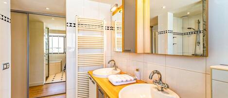 Een moderne badkamer met twee wasbakken, een grote spiegel en een handdoekhouder.