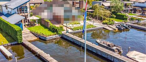 Une propriété située au bord de la rivière, dotée d’un quai, d’un mât pour drapeau et d’un petit bateau.