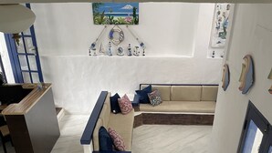 A modern interior with a staircase leading to a lower level, a sofa with cushions, and nautical-themed wall art. - Pousada Bicho do Mar (Arraial do Cabo)