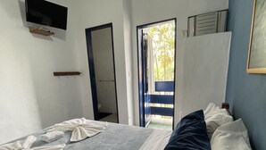 A bedroom with a bed, a television mounted on the wall, and a door leading to an outdoor area. - Pousada Bicho do Mar (Arraial do Cabo)