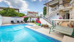 A swimming pool with a stone house in the background, a small playhouse, and a staircase leading to a balcony with flowers. - Amazing apartment in Valbandon with WiFi (Valbandon)