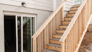 Una escalera de madera que lleva a una puerta blanca con un panel de vidrio.