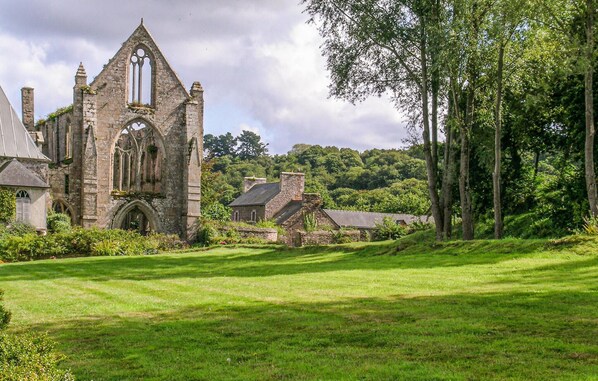 An old stone church with a large arched window and a bell tower, surrounded by lush greenery and a well-maintained lawn. - 2 bedroom gorgeous home in Quemper Guezennec (Quemper Guezennec)