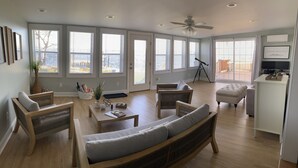 Un salon spacieux dot é de grandes fenêtres, d’un ventilateur de plafond et offrant une vue sur l’extérieur.