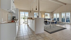 Una cocina amplia con una isla central, ventanas grandes y un techo alto.