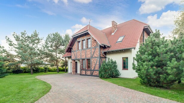 A two-story house with a brick facade, a red-tiled roof, and a paved driveway leading to the entrance. - Awesome home in Wygon with WiFi (Wygon)