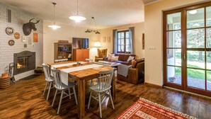 A cozy living room with a fireplace, a dining area with a wooden table and chairs, and a large window with a view of the outdoors. - Awesome home in Wygon with WiFi (Wygon)