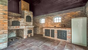 A rustic kitchen with a brick fireplace, two windows, and a refrigerator. - Awesome home in Wygon with WiFi (Wygon)