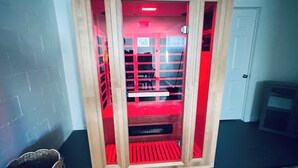 Una habitación con un mueble de madera con puertas de cristal, una alfombra estampada, una cesta tejida y un taburete de madera pequeño.