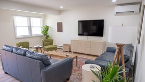 Una sala de estar moderna con un sofá gris, una mesa de centro, un televisor y una lámpara.
