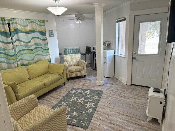 A living room with a yellow sofa, a beige armchair, and a star-patterned rug.
