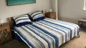 A bedroom with a bed, a nightstand, a lamp, and a painting of a beach scene. - Private In Law Unit In Beachfront Neighborhood Steps To Sand Walk To Restaurants (Half Moon Bay)