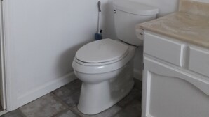 A bathroom with a toilet, a mop, and two abstract paintings on the wall. - Private In Law Unit In Beachfront Neighborhood Steps To Sand Walk To Restaurants (Half Moon Bay)