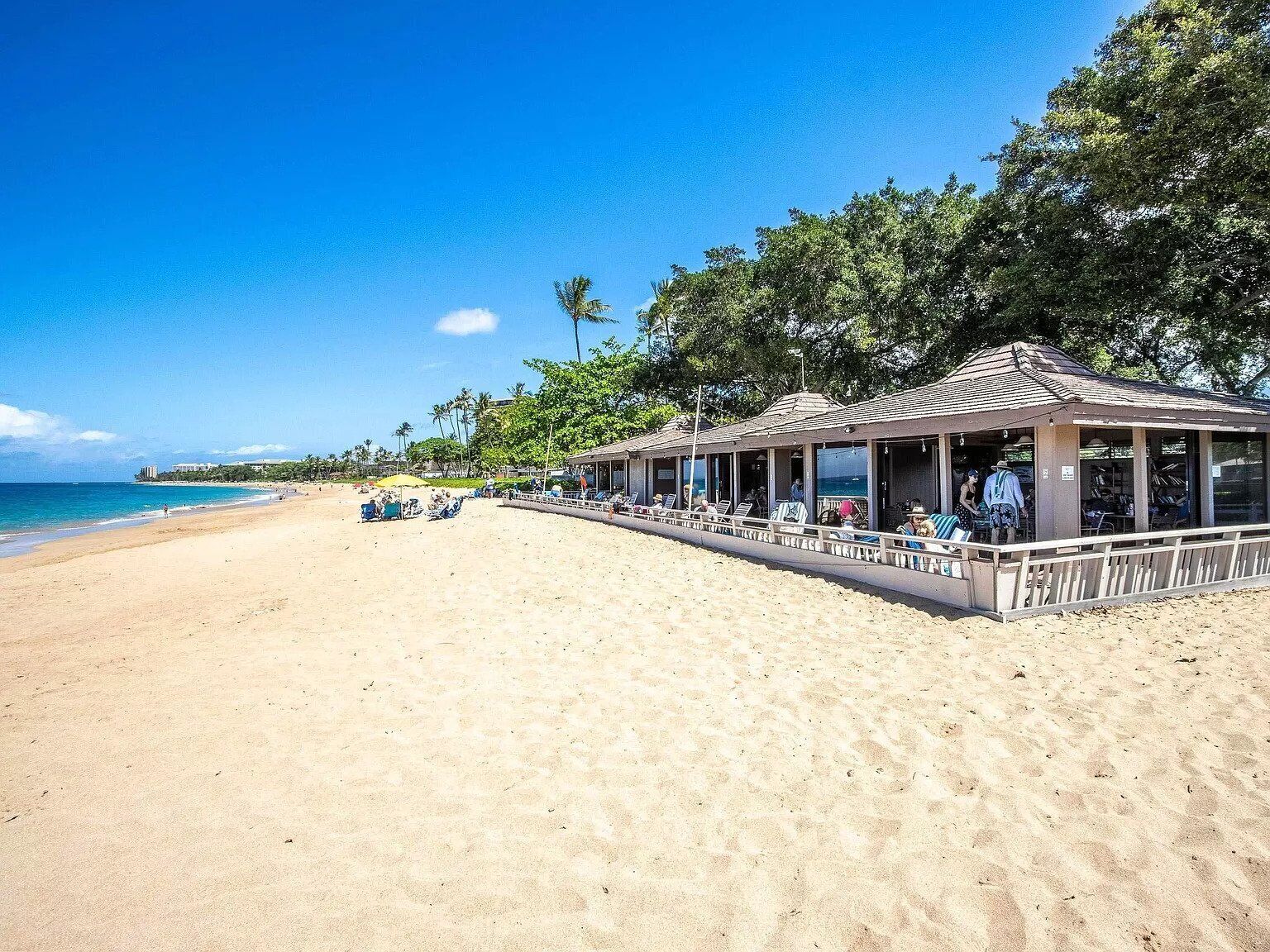 Un complexe hôtelier situé en bord de mer, doté d’un espace salon couvert et offrant une vue sur l’océan.