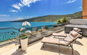 Un balcon avec vue sur la mer, un jacuzzi et des chaises longues.