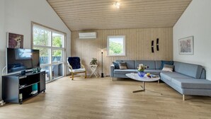 A modern living room with a television, a blue chair, a grey sofa, and a coffee table. - Cozy home in Hurup Thy with sauna (Hurup Thy)
