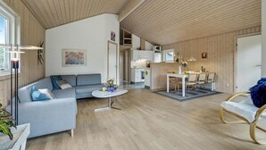 A modern living room with a grey sofa, a round coffee table, and a dining area with a white table and chairs. - Cozy home in Hurup Thy with sauna (Hurup Thy)