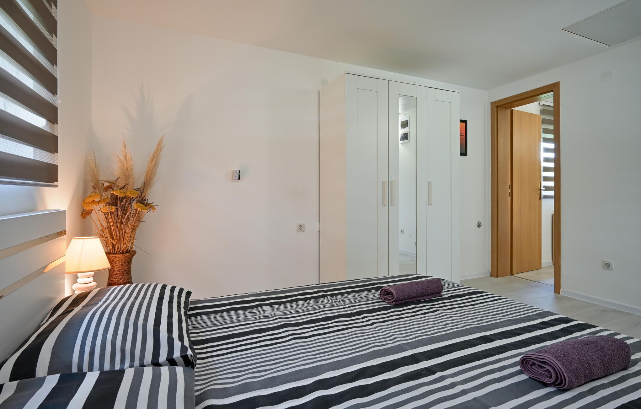 Una camera da letto con un letto, un comodino, una lampada e una pianta in vaso.