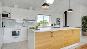 Een moderne keuken met witte kasten, een groot eiland en een dakraam.