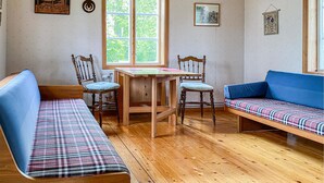 Um quarto acolhedor com piso de madeira, duas cadeiras de madeira, uma mesinha e um sofá azul.