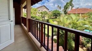Un balcón con vistas a una zona residencial, con casas y palmeras.