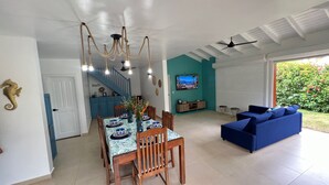 Un comedor con una mesa lista para cuatro, un sofá azul y un televisor montado en una pared verde azulado.