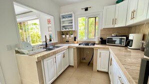 Una cocina moderna con armarios blancos, estufa a gas, microondas y cafetera.