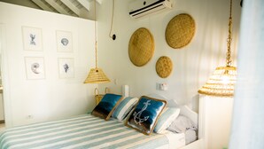 Un dormitorio con cama, almohadas, una lámpara colgante y adornos en la pared.