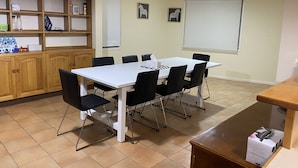 A conference room with a white table, black chairs, a wooden cabinet with shelves, and a projector screen. - Hawker 4BR House（Air-Con, WiFi, Netflix, Parking） (Hawker)