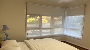A bedroom with a bed, a nightstand, a lamp, and a window with blinds. - Hawker 4BR House（Air-Con, WiFi, Netflix, Parking） (Hawker)