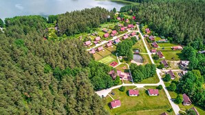 An aerial view of a residential area with houses, a lake, and a forested area.