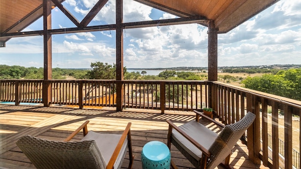 A wooden deck with a view of a lake and hills.