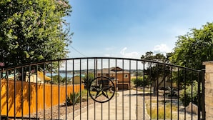A gated entrance with a star emblem, a pathway leading to houses, and a clear sky.