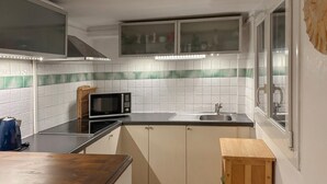 Cocina compacta con microondas, pileta y mostrador de madera.