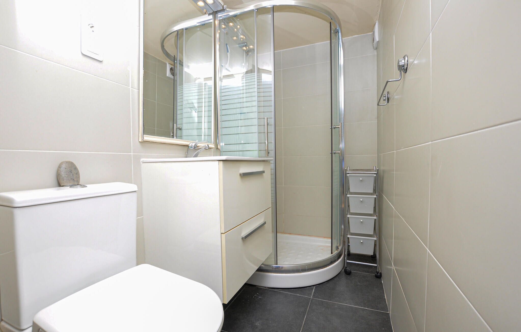 A modern bathroom with a glass-enclosed shower, a toilet, and a sink.