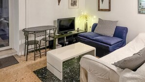 Una sala de estar con sofá, una mesita, televisor y una lámpara decorativa.
