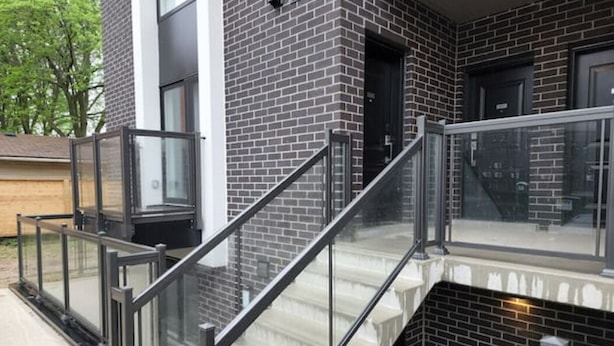 Un edificio moderno con fachada de ladrillo, escalera de cristal y barandilla metálica.