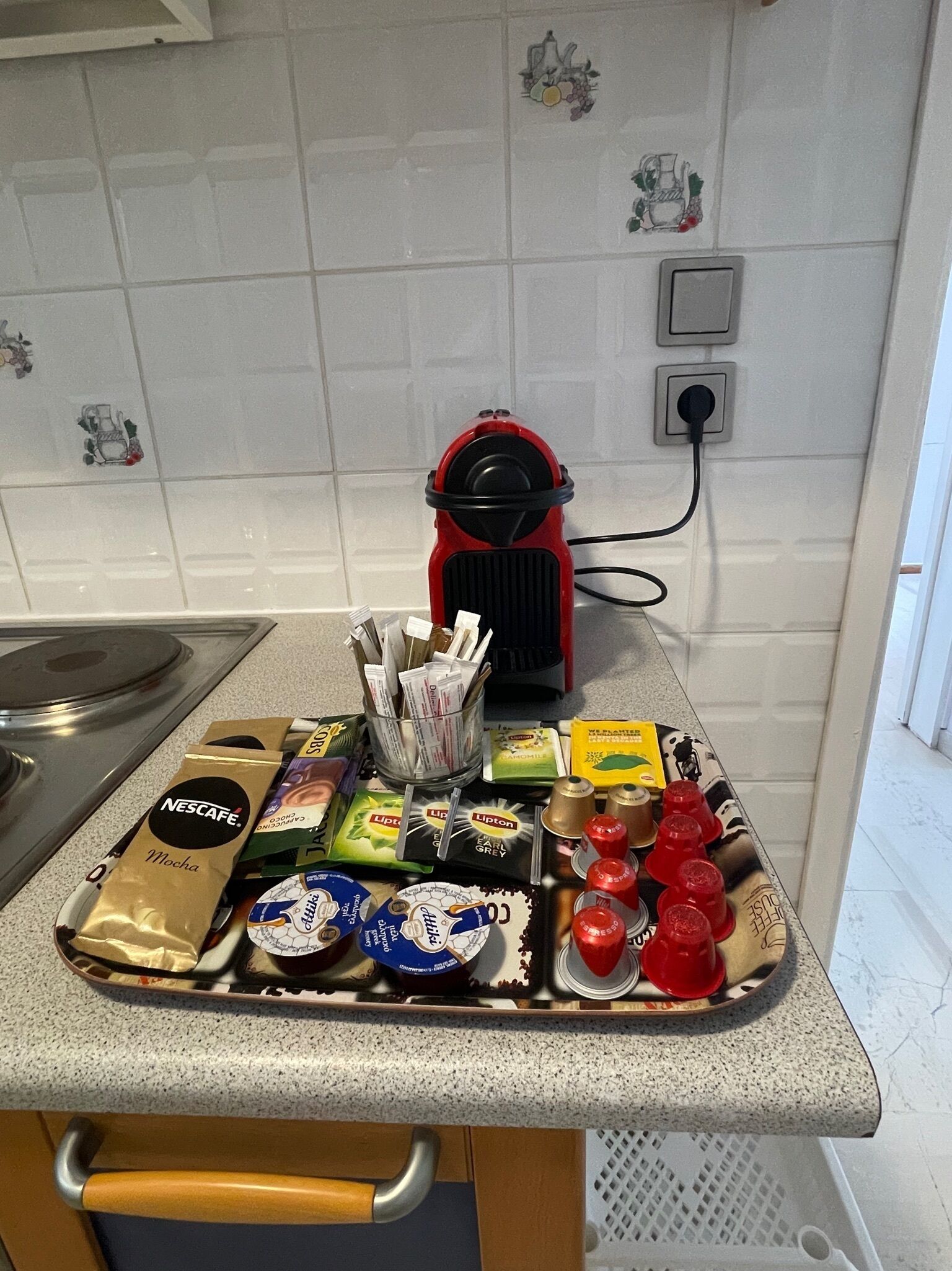 A kitchen counter with a coffee machine, various food items, and a power outlet.