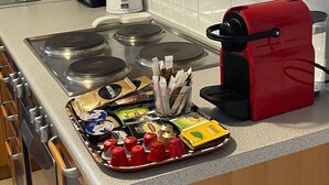 Een keuken met een fornuis, een rode koffiezetapparaat en diverse etenswaren op het aanrecht.