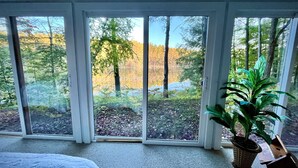 A room with a large sliding glass door leading to a forested area. - Big Twin Lodge-Fall Color Haven! Off-Roading, Snowmobiling, Wooded Seclusion! (Mancelona)