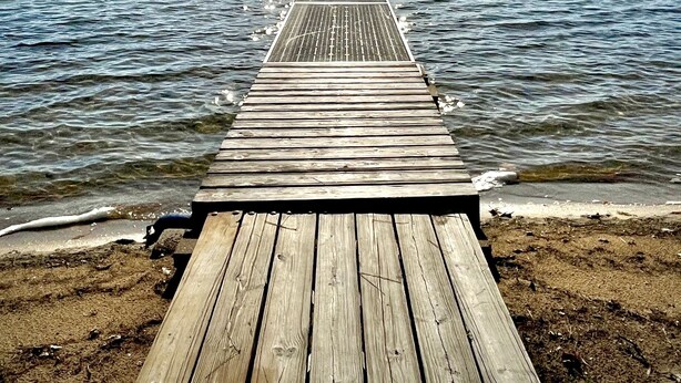 A wooden pier extending into calm water with a clear sky above. - Big Twin Lodge-Fall Color Haven! Off-Roading, Snowmobiling, Wooded Seclusion! (Mancelona)