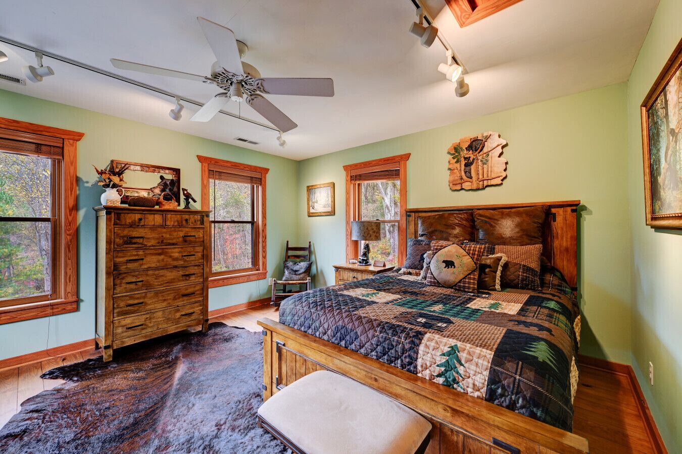 A bedroom with a large bed, wooden dresser, and a ceiling fan.