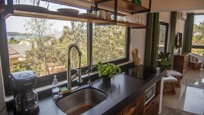 Una cocina moderna con un ventanal grande, una cafetera y un lavamanos.