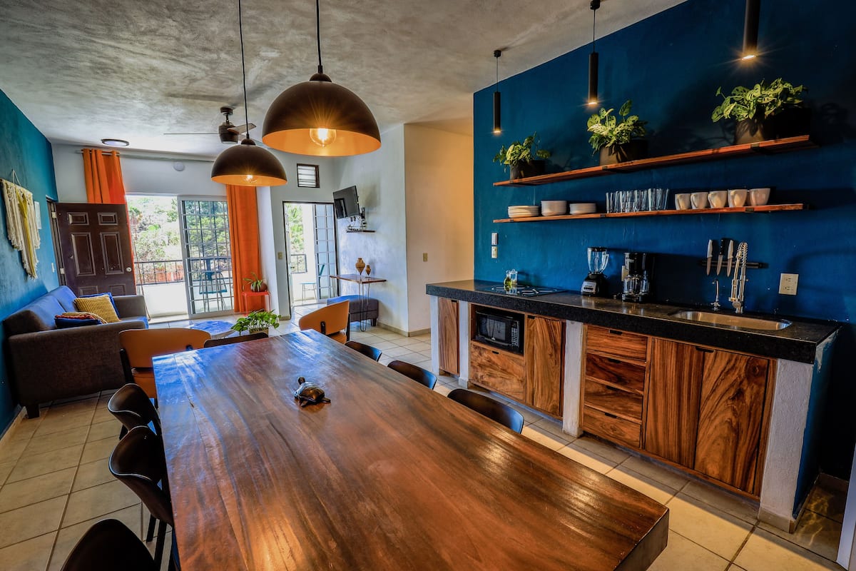 A modern kitchen with a wooden dining table, built-in appliances, and blue accent walls.