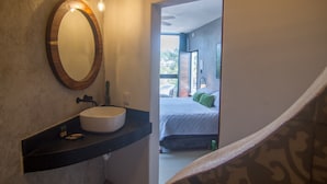 Un baño con un espejo redondo, un lavabo blanco y una lámpara sobre él.