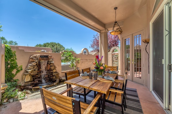 Relax in a sheltered outdoor space with a patio water feature, dining table, and comfortable seating under a pergola.