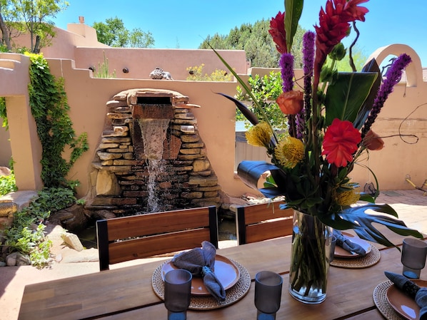 Une table à manger dressée avec des assiettes, des couverts et un vase rempli de fleurs.